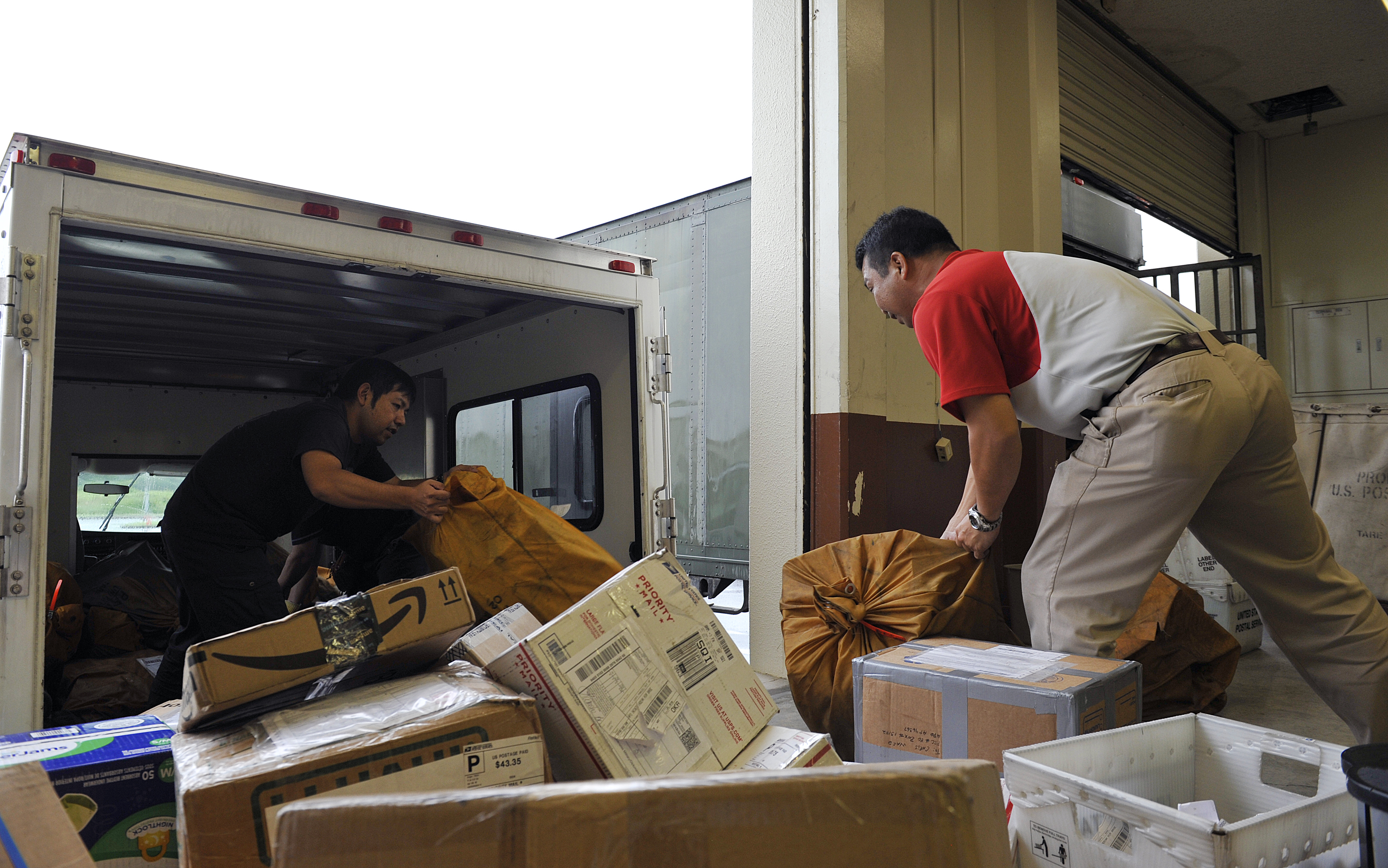 Japanese employees from the Kadena Post Office unload packages from a truck April 12, 2016, at Kadena Air Base, Japan. The post office typically processes approximately 500 packages a day during non-holiday seasons. (U.S. Air Force photo by Naoto Anazawa)